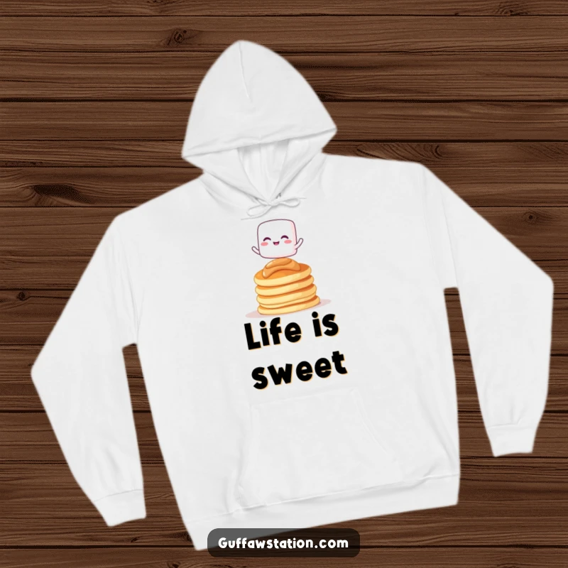 Funny hoodie with a giggling marshmallow character balancing on pancakes, perfect for warmth and sweet smiles.