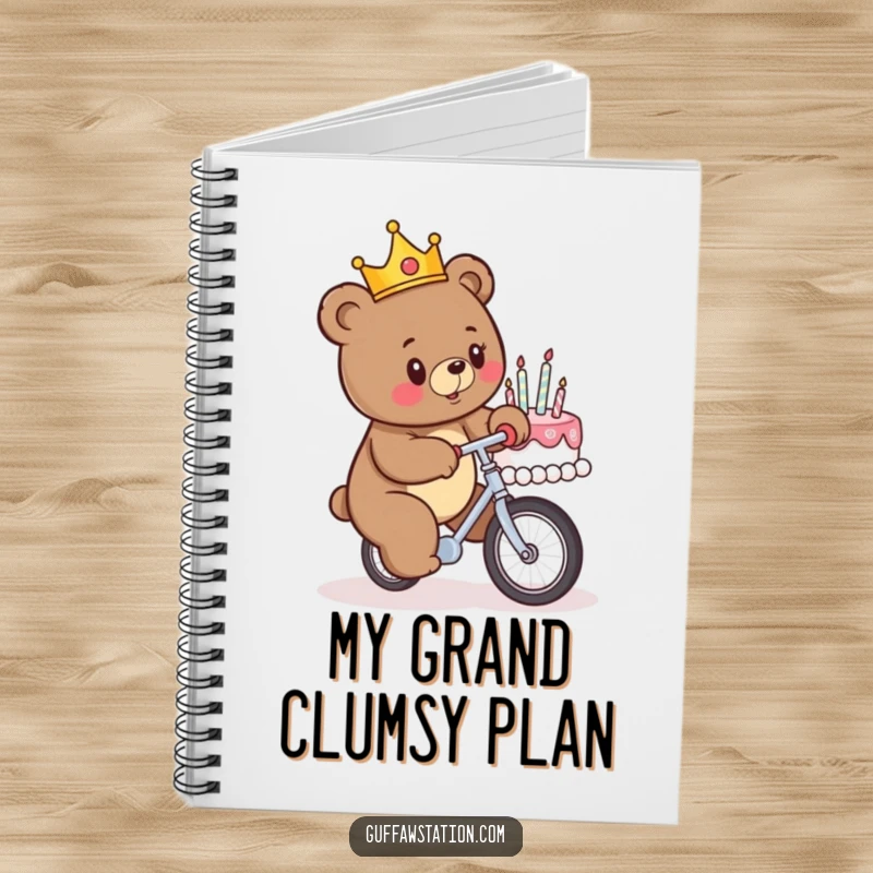 Funny notebook with a crowned bear attempting to unicycle into a birthday cake on the cover, inspiring humorous thoughts and notes.